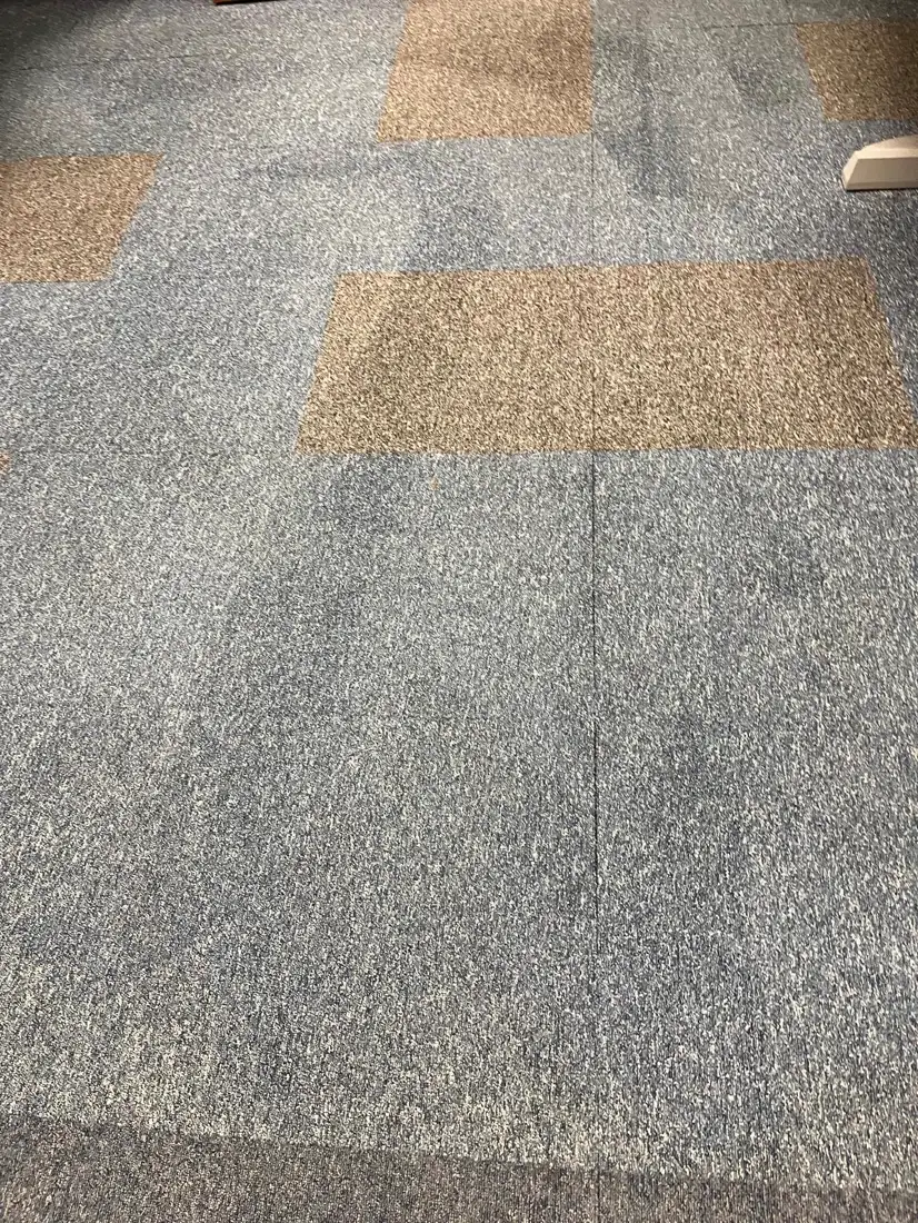 Stained carpet tiles in an office before cleaning